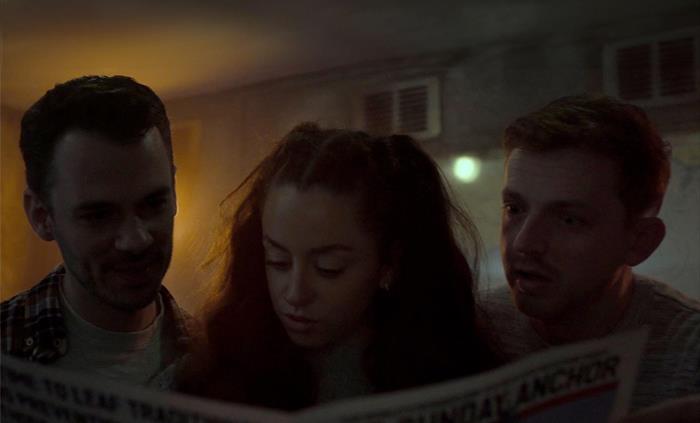 3 players are reading a newspaper in an escape room setting.